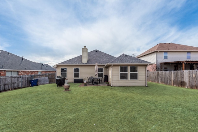 back of house featuring a fenced backyard, a yard, roof with shingles, a chimney, and a patio area