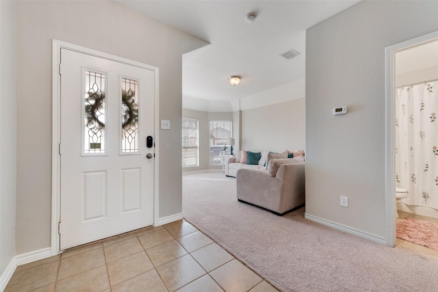 entryway with light tile patterned floors, baseboards, visible vents, and light carpet