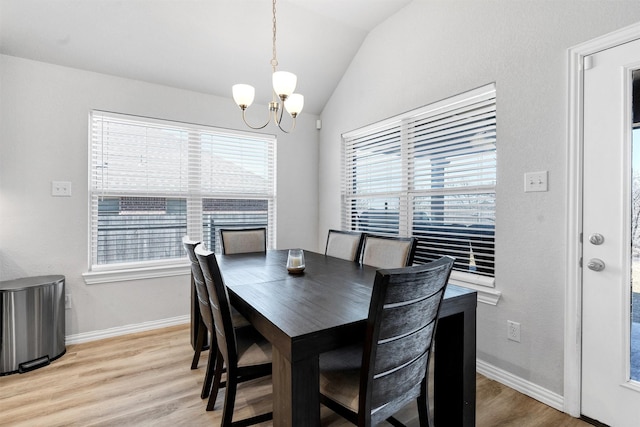 dining area with light wood finished floors, a notable chandelier, baseboards, and lofted ceiling