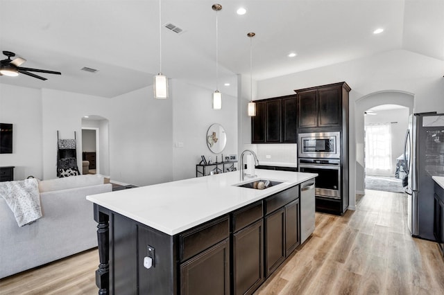 kitchen with open floor plan, arched walkways, appliances with stainless steel finishes, and a sink