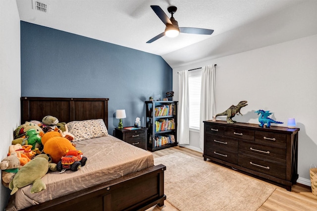 bedroom featuring a ceiling fan, baseboards, visible vents, lofted ceiling, and light wood-style flooring