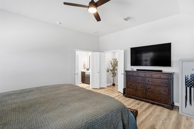 bedroom featuring a ceiling fan, visible vents, light wood-style flooring, vaulted ceiling, and connected bathroom