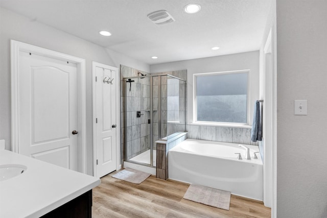 bathroom featuring a shower stall, a bath, wood finished floors, and visible vents