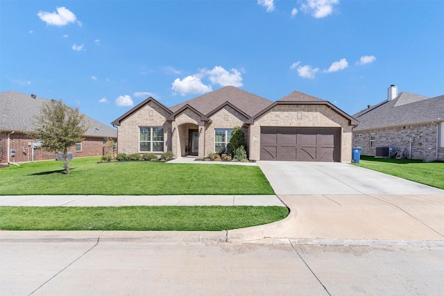 french provincial home featuring driveway, a front lawn, central AC, an attached garage, and brick siding