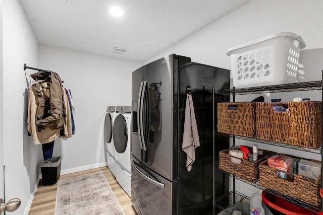 washroom featuring baseboards, light wood finished floors, laundry area, and washing machine and clothes dryer