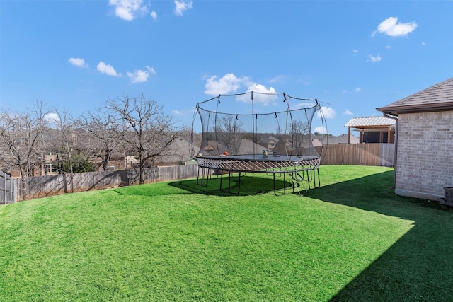 view of yard with a trampoline and a fenced backyard