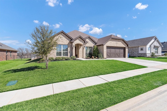 french country inspired facade featuring brick siding, an attached garage, a front lawn, fence, and driveway