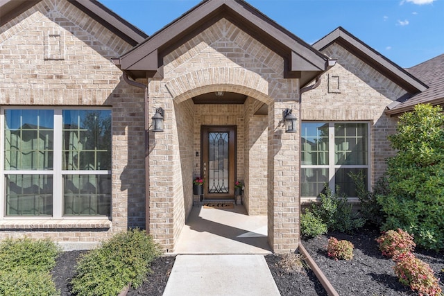 view of exterior entry featuring brick siding