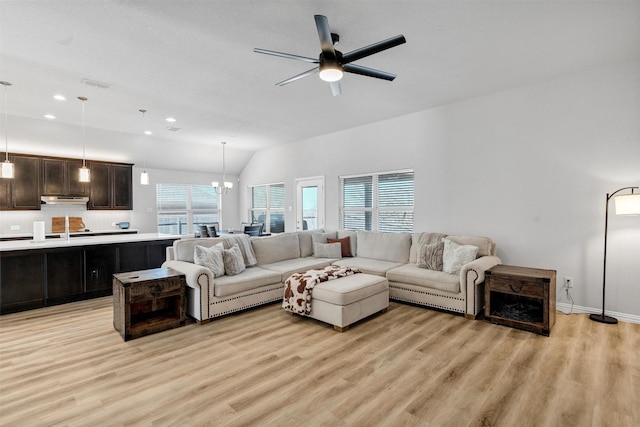 living area featuring visible vents, light wood-style flooring, ceiling fan with notable chandelier, and lofted ceiling