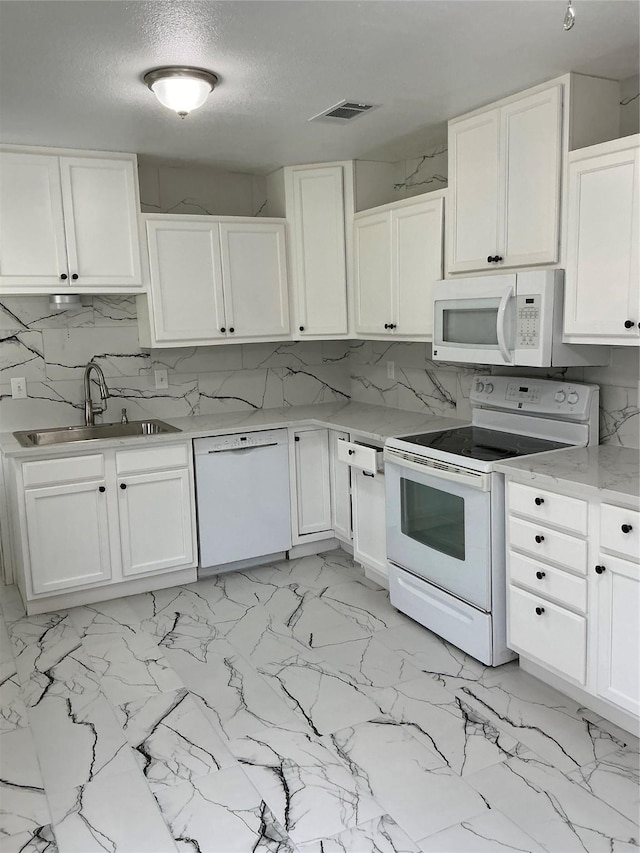 kitchen with decorative backsplash, white appliances, white cabinets, and a sink