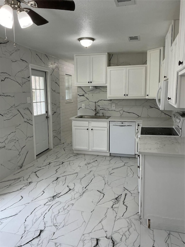 kitchen with white appliances, visible vents, a sink, light countertops, and white cabinets