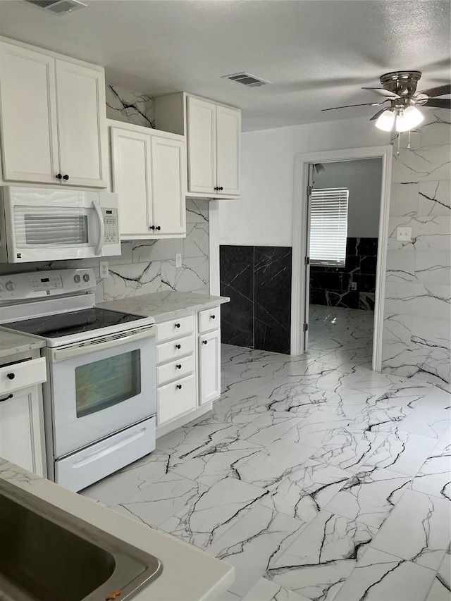 kitchen with white appliances, white cabinets, light countertops, and a textured ceiling