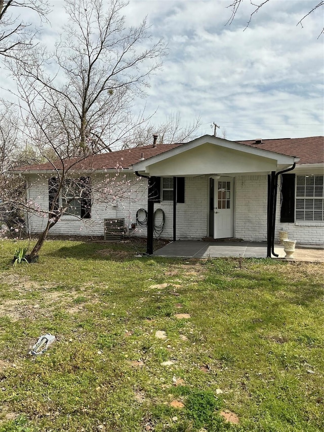 view of front of property featuring a patio, brick siding, and a front yard