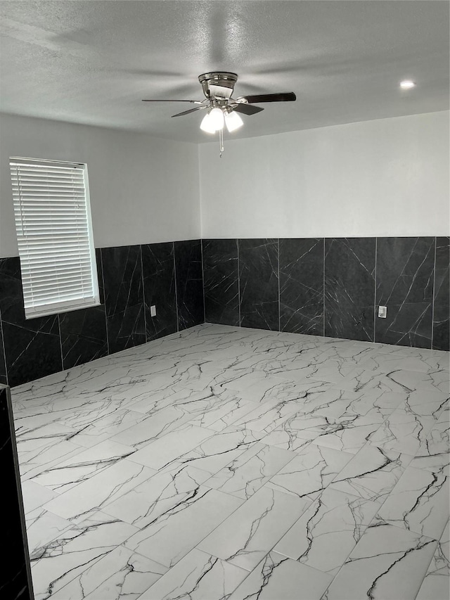 unfurnished room with a ceiling fan and a textured ceiling