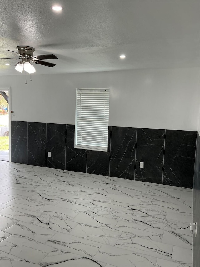 interior space with recessed lighting, a ceiling fan, and a textured ceiling