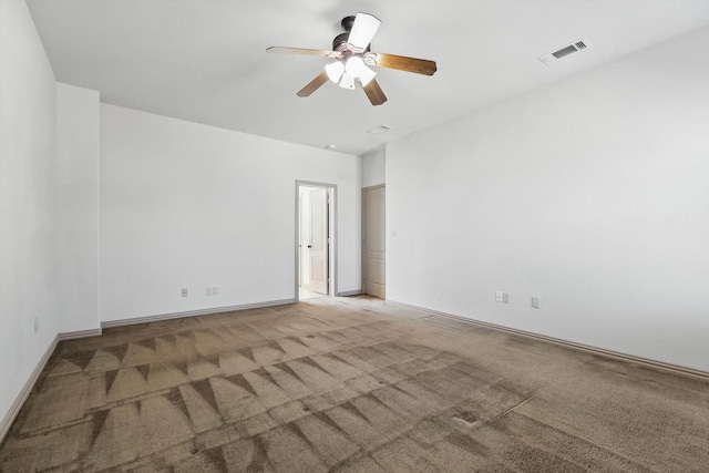 empty room featuring a ceiling fan, carpet, visible vents, and baseboards