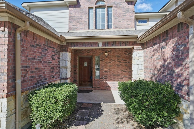 property entrance with brick siding and roof with shingles