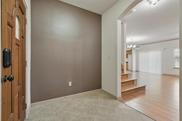 interior space featuring baseboards, a chandelier, stairway, light tile patterned floors, and arched walkways