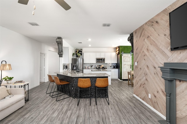 kitchen featuring light stone counters, stainless steel appliances, a kitchen bar, and visible vents