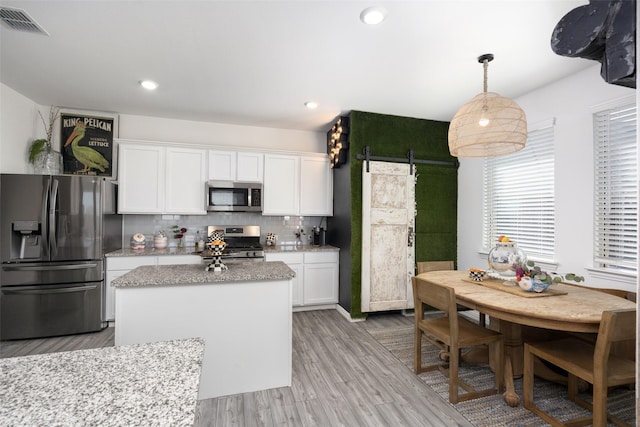 kitchen featuring visible vents, light wood-type flooring, decorative backsplash, appliances with stainless steel finishes, and white cabinetry