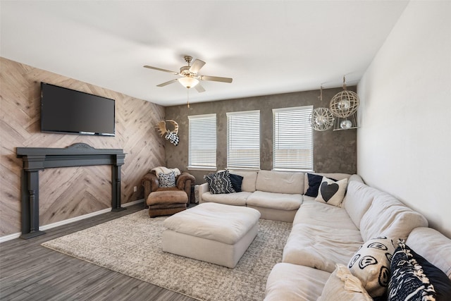 living room featuring a fireplace, wood finished floors, baseboards, and ceiling fan