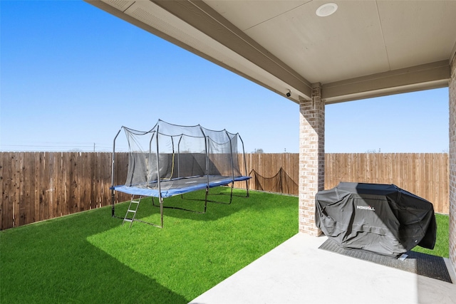 view of yard with a fenced backyard, a patio area, and a trampoline