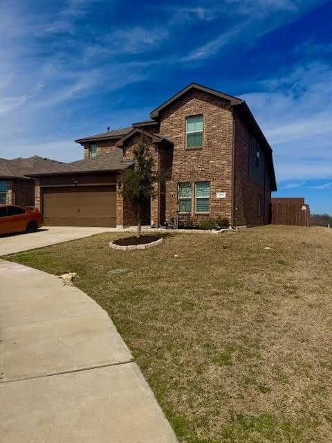 view of front of house featuring brick siding, fence, concrete driveway, a front yard, and a garage