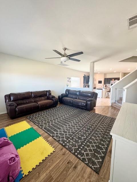 living area featuring visible vents, ceiling fan, and wood finished floors