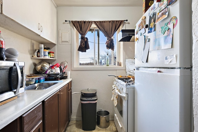 kitchen featuring white appliances, a sink, light countertops, dark brown cabinets, and under cabinet range hood