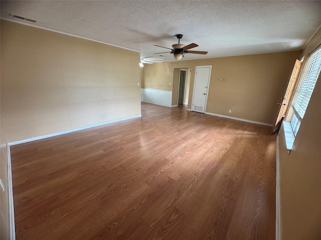 empty room with light wood finished floors, visible vents, baseboards, ceiling fan, and a textured ceiling