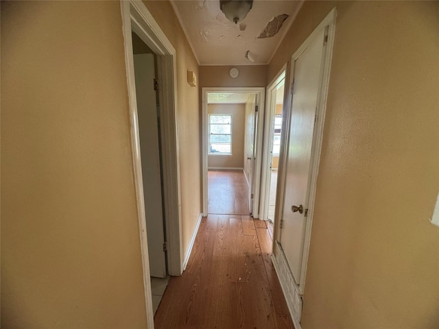 corridor with light wood-style flooring and baseboards