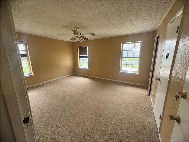 spare room with a textured ceiling, baseboards, and light carpet