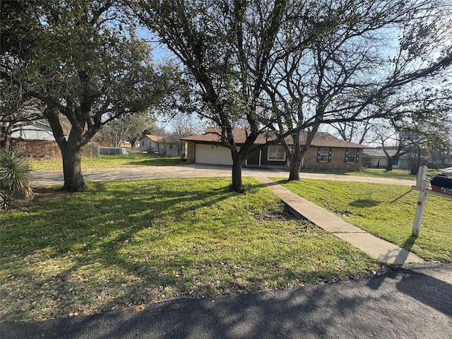 single story home featuring a front lawn, a garage, and driveway