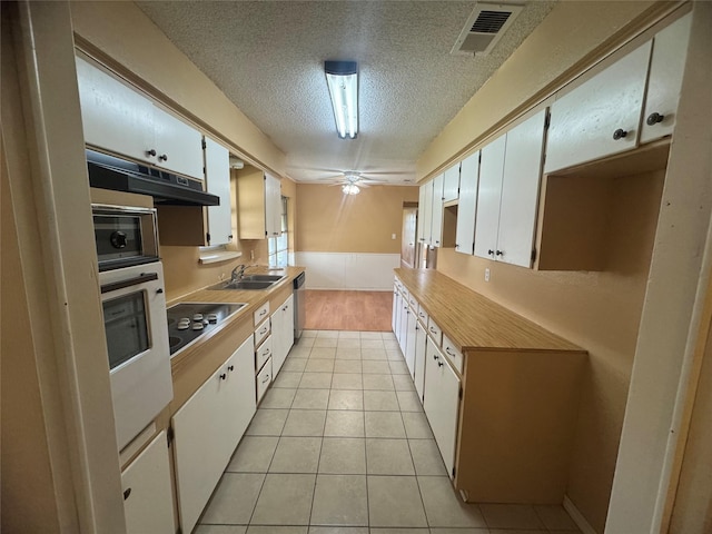 kitchen with visible vents, oven, black electric stovetop, under cabinet range hood, and a sink