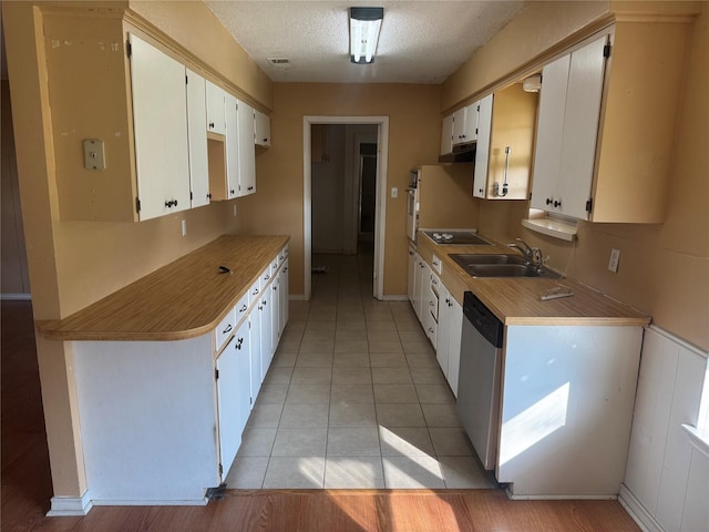 kitchen with light tile patterned floors, a sink, a textured ceiling, dishwasher, and black electric cooktop