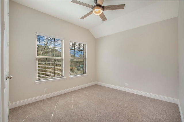 carpeted empty room featuring vaulted ceiling, baseboards, and ceiling fan