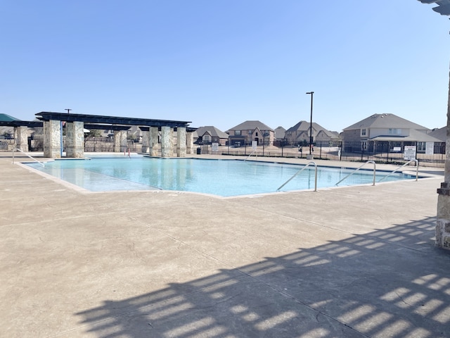 community pool featuring a patio area, a residential view, and fence