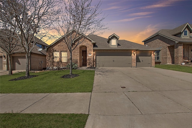 view of front of property with brick siding, a shingled roof, a front lawn, driveway, and an attached garage