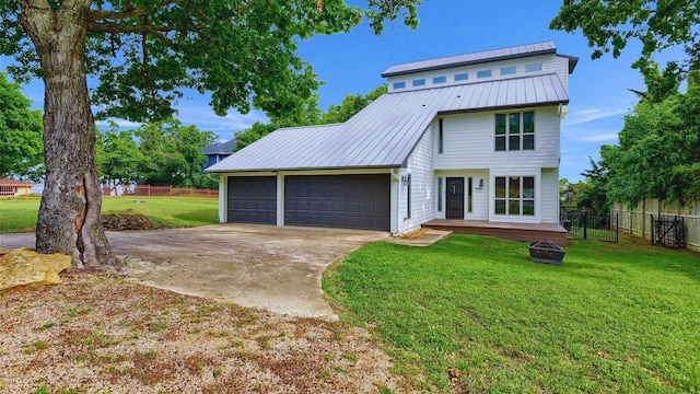 view of front of home with a standing seam roof, an attached garage, a front lawn, and fence