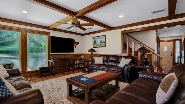 living room with a ceiling fan, visible vents, a wainscoted wall, stairs, and beamed ceiling