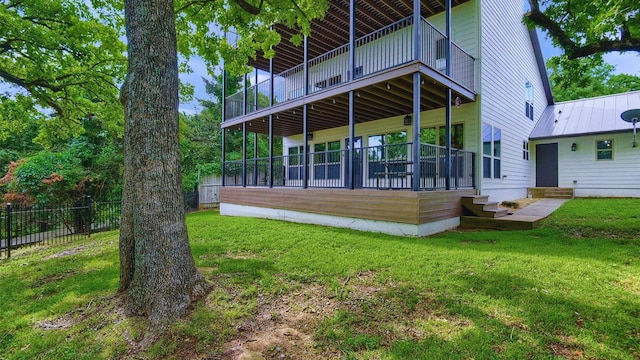 rear view of property featuring a standing seam roof, a lawn, fence, and metal roof