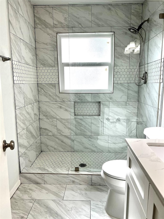 full bath featuring toilet, marble finish floor, a stall shower, and vanity