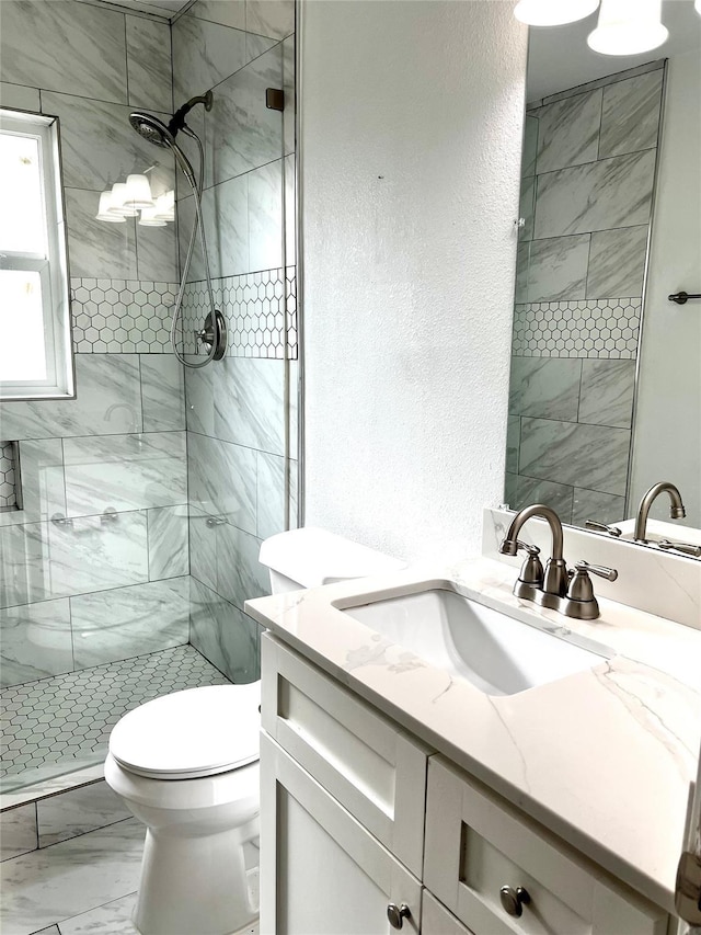 bathroom featuring vanity, a shower stall, toilet, a textured wall, and marble finish floor