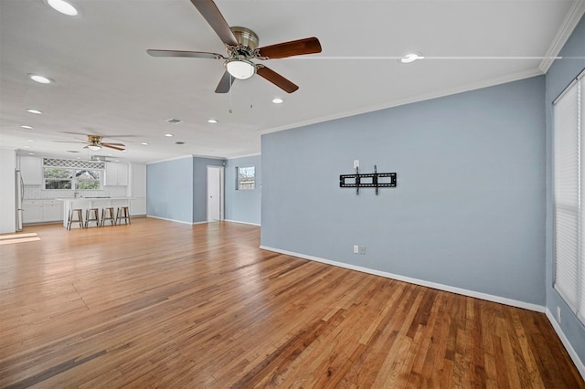 unfurnished living room featuring baseboards, recessed lighting, ceiling fan, crown molding, and light wood-type flooring