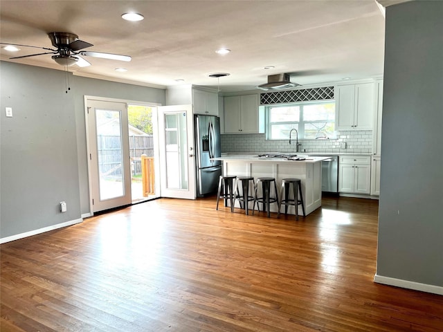 kitchen featuring decorative backsplash, appliances with stainless steel finishes, a breakfast bar, and dark wood-type flooring