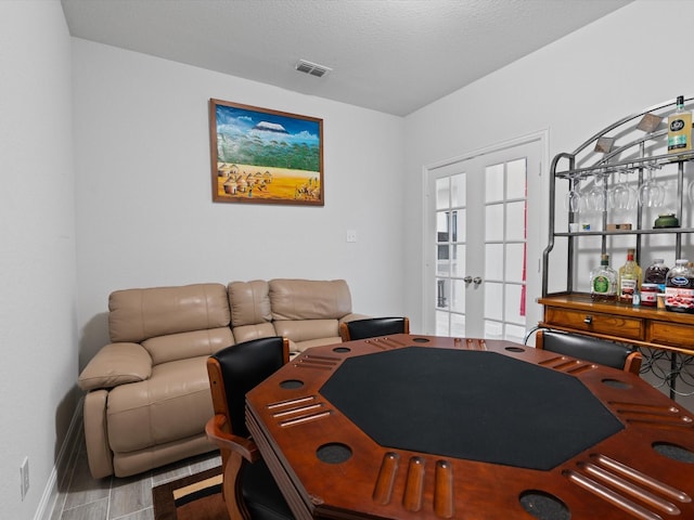 living room with visible vents, french doors, a textured ceiling, and baseboards