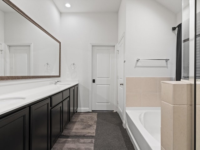 bathroom featuring a sink, a garden tub, and double vanity