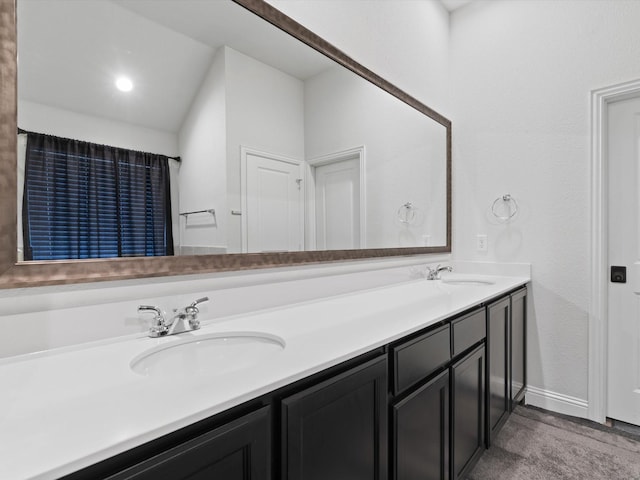 bathroom featuring double vanity, baseboards, and a sink