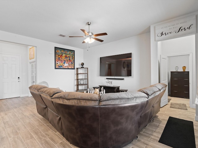 living room featuring wood finish floors, visible vents, baseboards, and ceiling fan