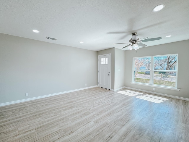 unfurnished living room featuring baseboards, visible vents, recessed lighting, a textured ceiling, and light wood-type flooring